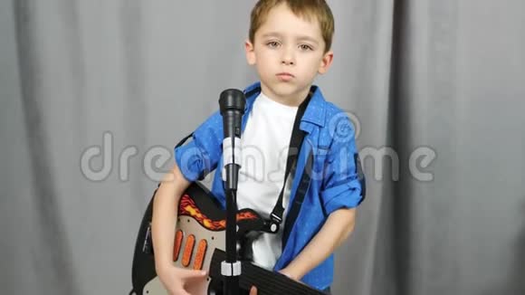 一个小男孩拿着吉他幼儿对着话筒唱歌幼儿播放和学习音乐视频的预览图