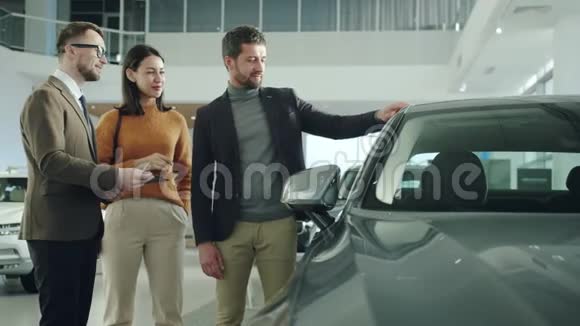 商人和漂亮的妻子选择汽车在经销商与推销员交谈视频的预览图