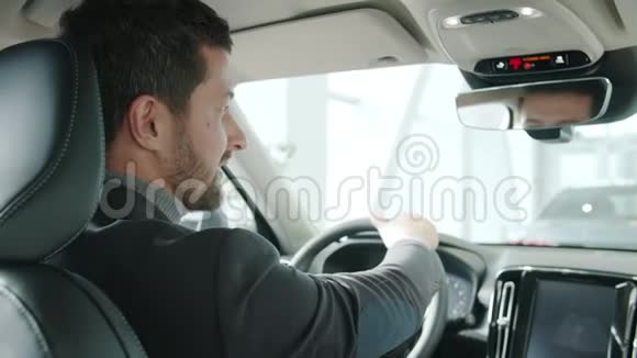 男人的肖像竖起大拇指坐在新车里微笑着看着摄像机视频的预览图