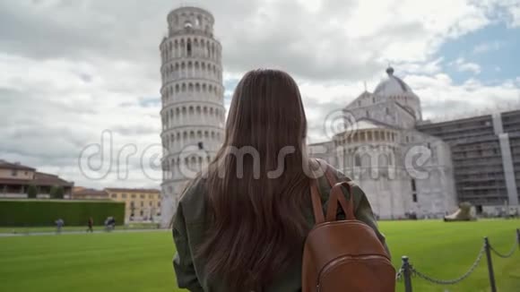 站在意大利比萨大教堂和比萨斜塔前的迪伊奇迹广场上的黑发女子的后景视频的预览图