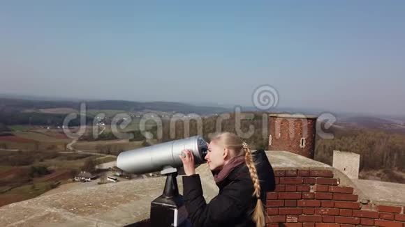 有魅力的女旅行者用望远镜观察古堡附近的山谷视频的预览图