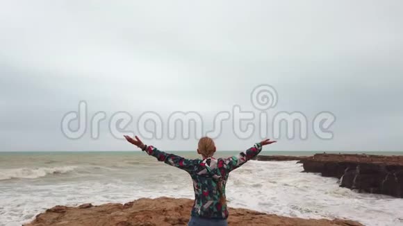 在暴风雨中女孩站在海边时举起双手视频的预览图