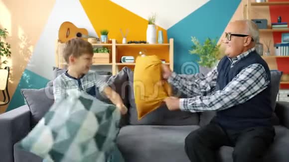 玩的人老人和可爱的男孩在家玩枕头大战视频的预览图