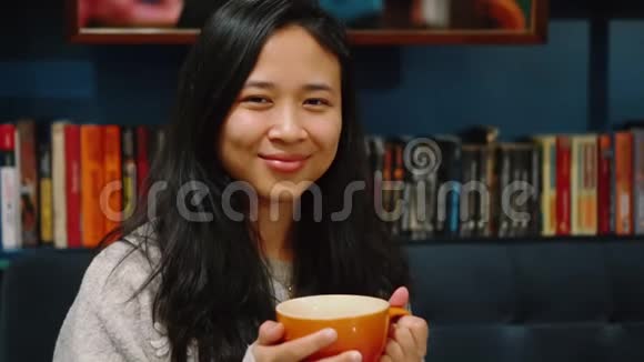 吸引人的年轻女人的肖像背景上的书架她喝咖啡视频的预览图