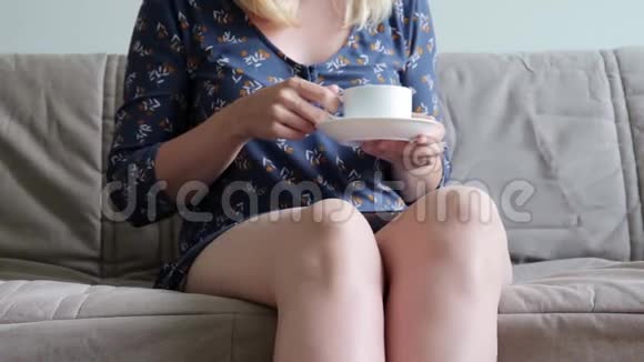坐在沙发上坐着教练喝着热咖啡或茶穿着休闲装的女人面目全非她在做了之后很放松视频的预览图