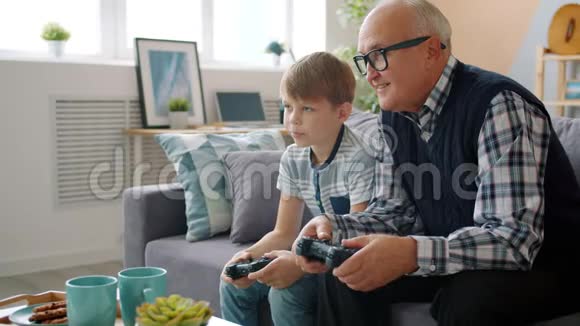 老人和快乐的孙子在家玩电子游戏视频的预览图