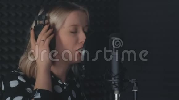 女歌手戴耳机唱歌麦克风录音歌曲在录音室视频的预览图