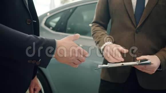 在和销售经理握手后把拿到车钥匙的男性手合上视频的预览图