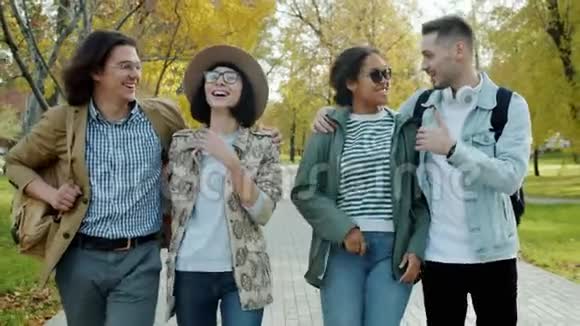 快乐的朋友游客带着背包在城市公园散步谈笑风生视频的预览图