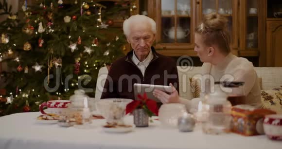 祖父在孙女手里拿着数字桌说话视频的预览图
