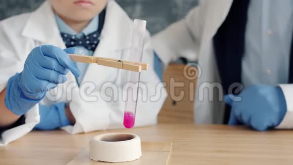 化学反应的特写由孩子和老师在燃烧器上加热玻璃管视频的预览图