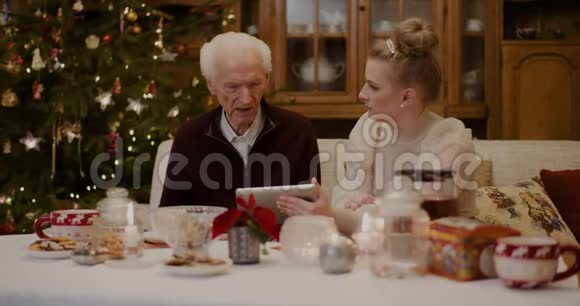 祖父在孙女手里拿着数字桌说话视频的预览图