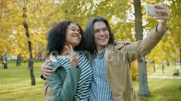 秋天公园的一对情侣用智能手机自拍视频的预览图