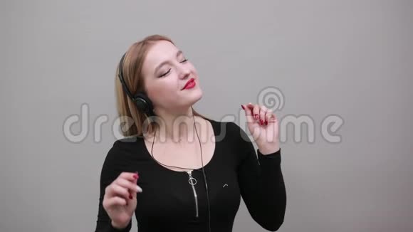 穿黑色夹克的女孩戴着耳机听音乐跳舞的可爱女人视频的预览图
