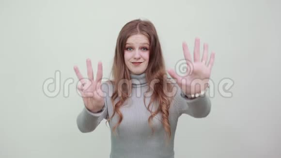穿灰色毛衣的女人用手指显示数字9视频的预览图