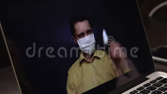 一位戴着医疗面具的视频博主正在笔记本电脑网络摄像头上录制广告视频他打广告给订户视频的预览图