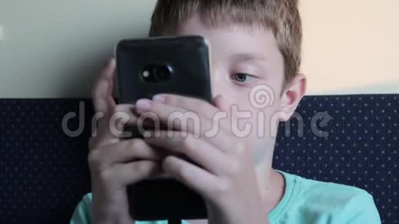 一个十几岁的男孩在智能手机上玩游戏同时坐火车旅行和旅行视频的预览图