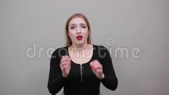 年轻的金发女孩穿着黑色夹克吓坏了的女人双手面对视频的预览图