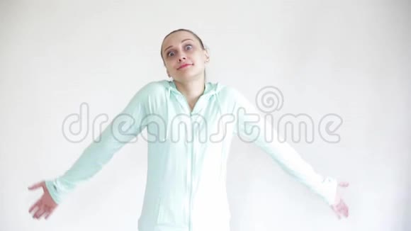 一个年轻的女人靠在一堵白色的墙上情绪地滚动着她的眼睛张开双臂不高兴地摇摇头视频的预览图