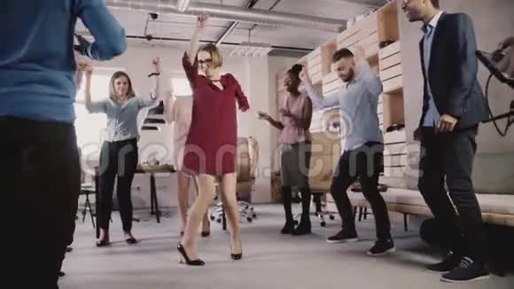 快乐的白种人女领导在休闲办公室聚会上跳舞多民族商人庆祝成功慢动作视频的预览图