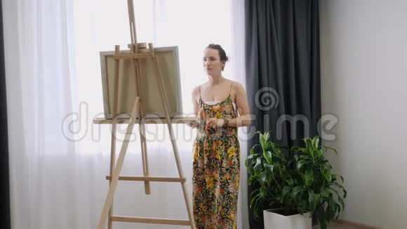 艺术家在画布上作画涂抹画笔帆布站在画架上女人在画架上画画女画工作室视频的预览图