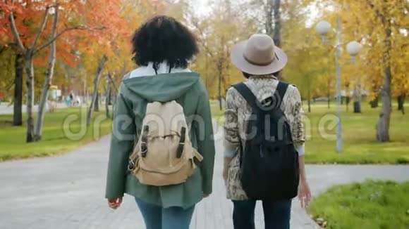 在城市公园里有吸引力的女孩朋友带着背包走路的慢动作视频的预览图