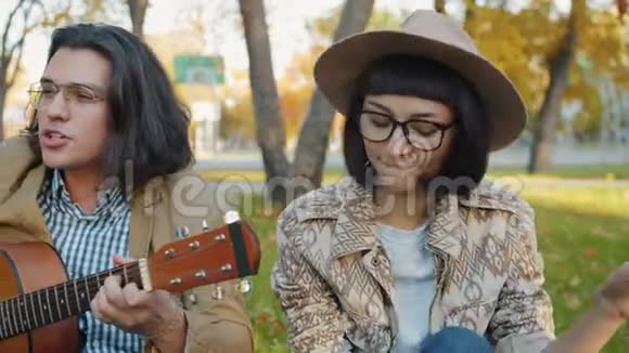 富有创造力的年轻人在城市公园里弹吉他的画像视频的预览图