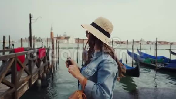 戴墨镜的女游客戴帽子在大运河上通过电话拍照视频的预览图