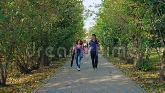 积极的青少年与女友牵手在公园散步视频的预览图