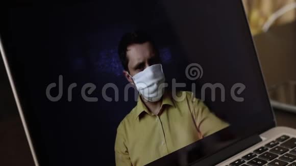 一位戴着医疗面具的视频博主正在笔记本电脑网络摄像头上录制广告视频他给他的订户赠送了视频的预览图