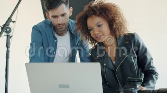 男子和妇女使用笔记本电脑在摄影棚观看照片后视频的预览图