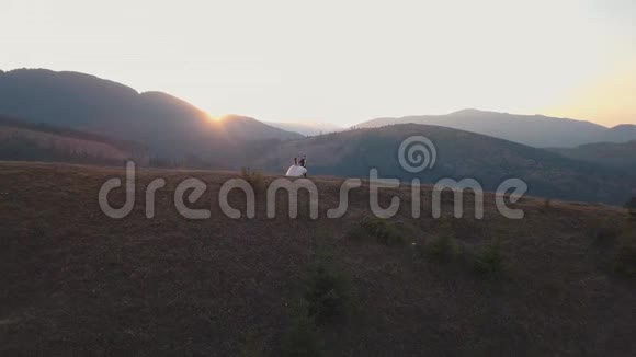 新婚夫妇在高山的高坡上奔跑新郎和新娘空中景观视频的预览图