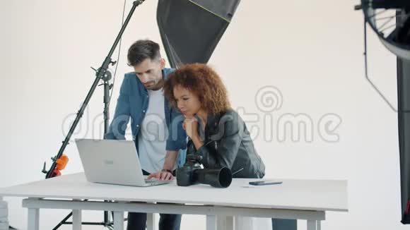 模特和摄影师使用笔记本电脑在演播室交谈享受商务交流视频的预览图