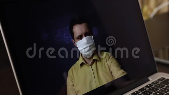 一位戴着医用口罩的视频博主正在笔记本电脑上录制一段广告视频的网络摄像头他向订户赠送了一个鼻视频的预览图