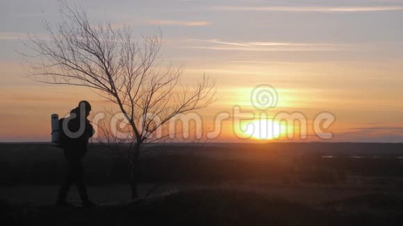 剪影孤独的人背着背包在山里在夕阳和夕阳下散步旅游概念视频的预览图