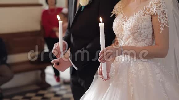 新婚夫妇新娘和新郎站在教堂里手里拿着蜡烛视频的预览图