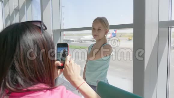 年轻的母亲在机场等他们的航班时在电话上拍了一张女儿的照片在国外旅行视频的预览图