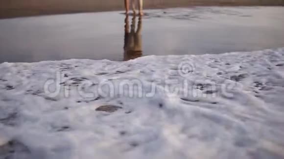 一对年轻夫妇站在沙滩海岸线上观看来自海洋的日落波浪戴着墨镜和休闲装视频的预览图