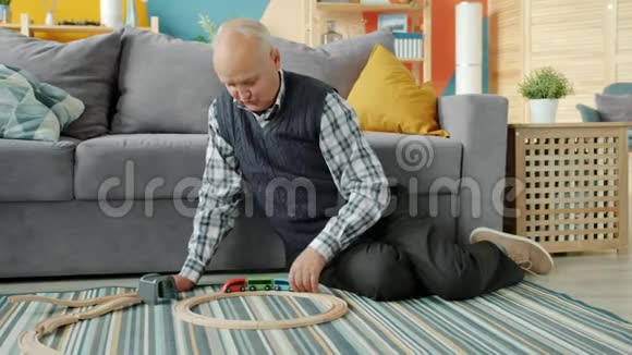 老人爷爷在室内玩移动玩具汽车坐在地上视频的预览图
