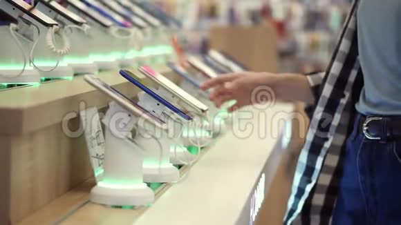 一个无法辨认的女人的腰部镜头她的手在一家电子商店里选择了一部智能手机她把智能手机从视频的预览图