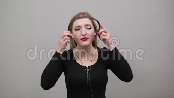 年轻的金发女孩穿着夹克带着耳机听音乐的女人很生气视频的预览图