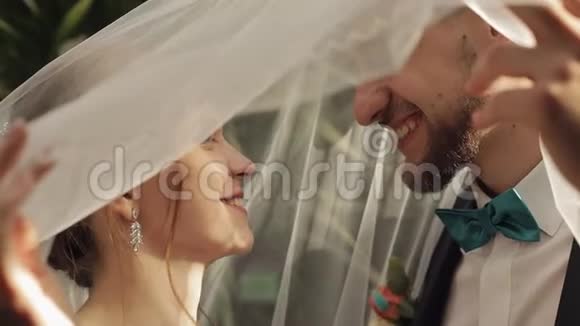 新婚夫妇白种人新郎新娘在面纱下接吻新婚夫妇视频的预览图