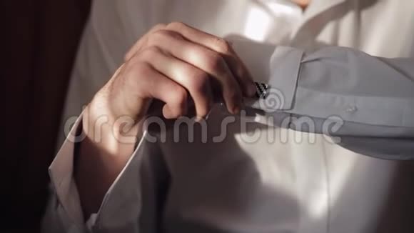 英俊的新郎把他的袖口用袖扣固定在衬衫上商人视频的预览图