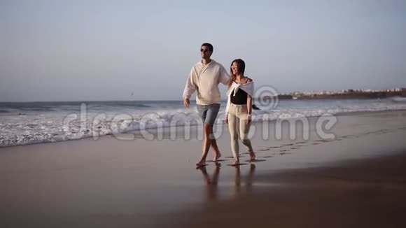情侣浪漫漫步沙滩情侣赤脚漫步沙滩夏天情侣相爱异国的假期风在招手视频的预览图
