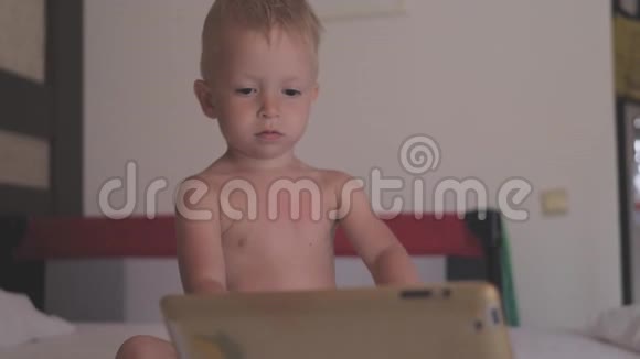 小男孩躺在床上在黑暗的光线下在社交网络上玩平板电脑视频的预览图