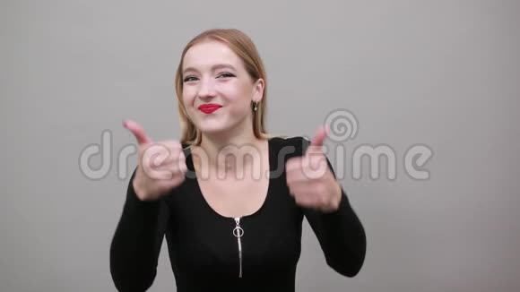 年轻的金发女孩穿着黑色夹克快乐的女人露出大拇指视频的预览图