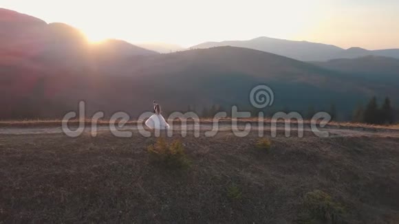 新婚夫妇走在高高的山坡上新郎和新娘空中景观视频的预览图