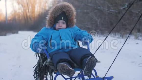 父母在冬天带着快乐的小男孩在雪橇上幼儿玩雪橇家庭圣诞节的户外乐趣视频的预览图