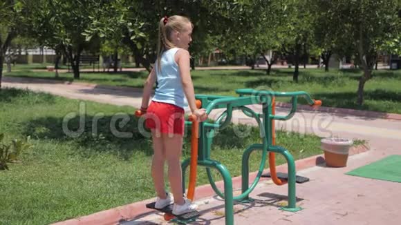 夏天在公园里女孩在街头运动设备上进行锻炼视频的预览图