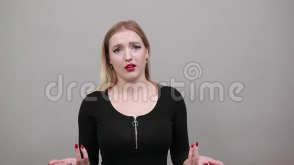年轻的金发女孩穿着黑色夹克困惑的女人张开双手视频的预览图